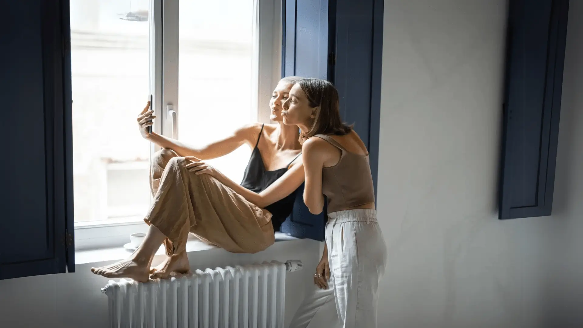 Deux femmes sur le rebord d'une fenêtre collé à un radiateur
